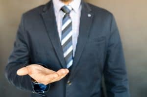 A man in a suit is holding out his hand.