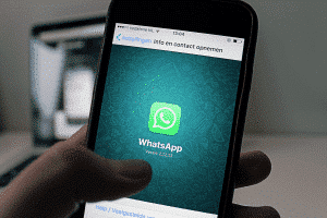 A person holding a phone with the whatsapp logo on it.
